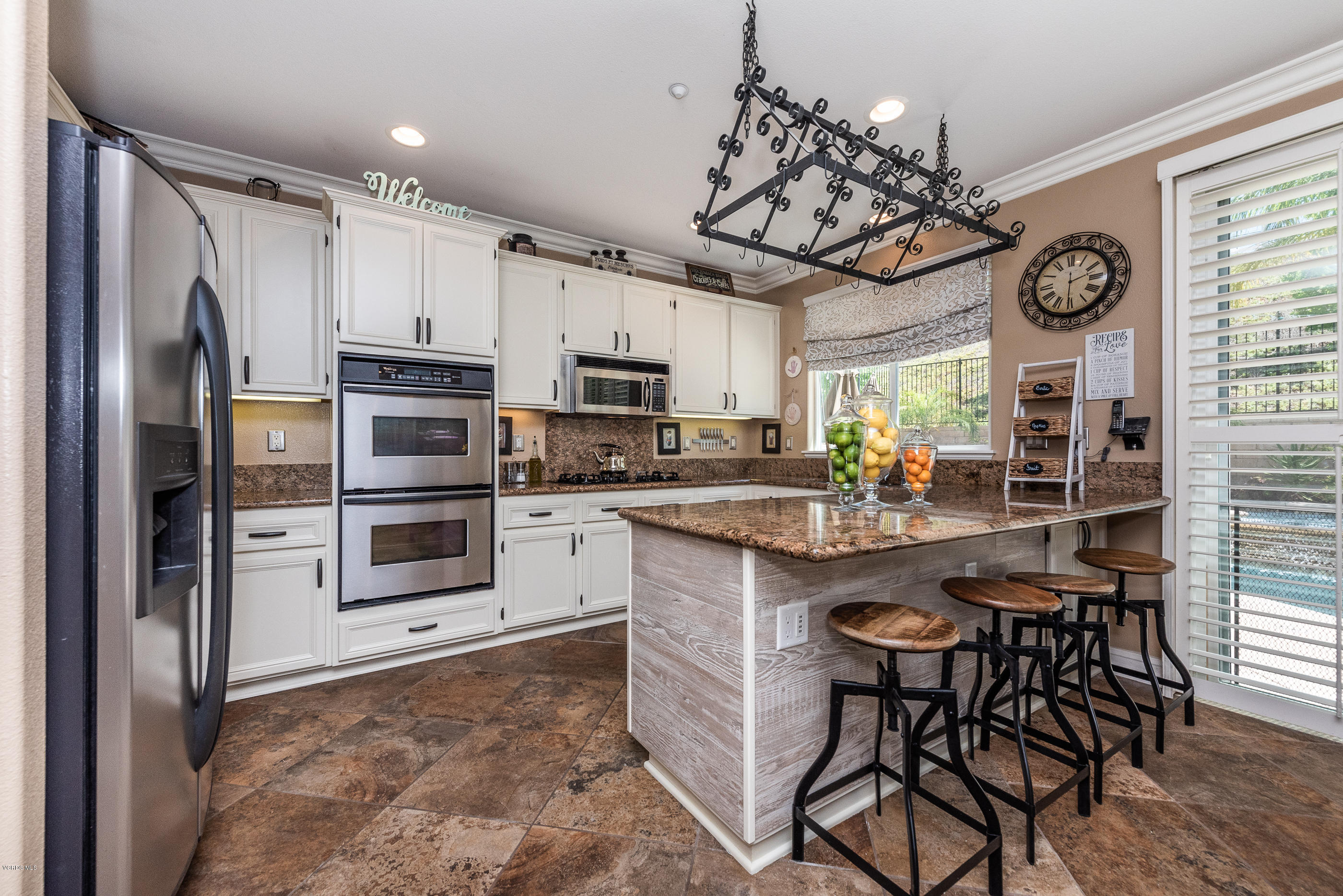 1469 Hidden Ranch Drive Simi Valley, CA 93063 - Photo 22 of 49 a kitchen with stainless steel appliances a table chairs refrigerator and microwave