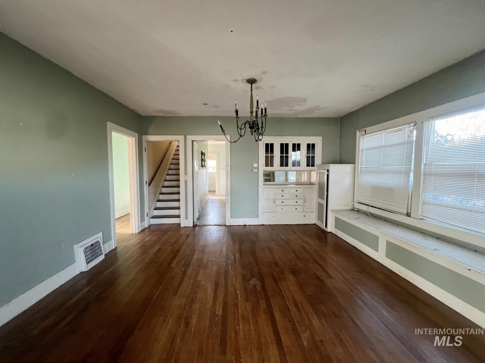 1002 9th Street Clarkston, WA 99403 - Photo 5 of 19 Unfurnished dining area featuring dark wood finished floors, stairway, healthy amount of natural light, and a chandelier