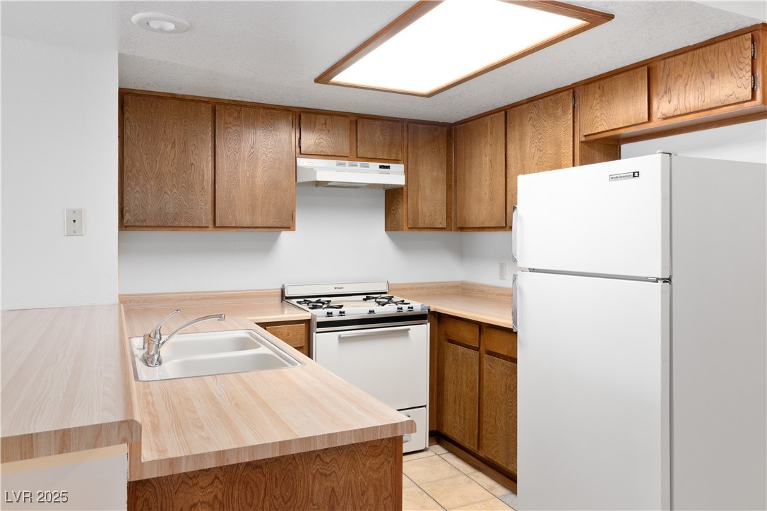 3740 Desert Marina Drive, Unit 2 Laughlin, NV 89029 - Photo 12 of 75 Kitchen featuring white appliances, light countertops, brown cabinets, and light tile patterned flooring