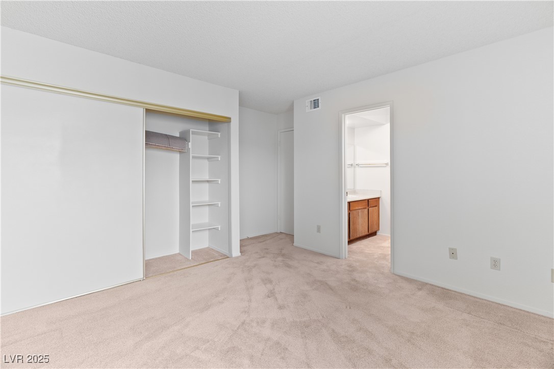 3740 Desert Marina Drive, Unit 2 Laughlin, NV 89029 - Photo 26 of 75 Primary bedroom featuring light colored carpet, a closet, and connected bathroom