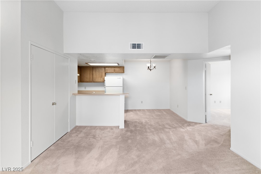 3740 Desert Marina Drive, Unit 2 Laughlin, NV 89029 - Photo 8 of 75 Living room and Dining area with Kitchen with light carpet, a peninsula, freestanding refrigerator, brown cabinets, and light countertops