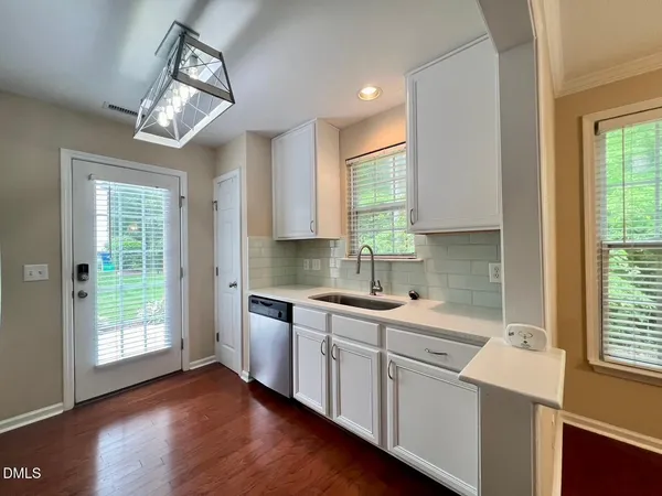 a kitchen with a sink dishwasher a stove a washer and dryer with wooden floor