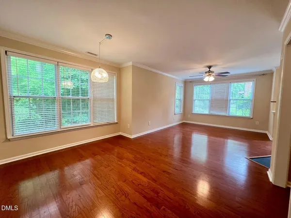 a view of an empty room with wooden floor and a window