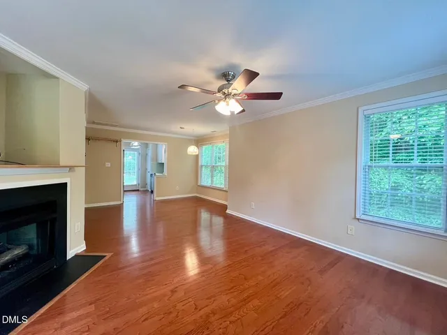 a view of an empty room with wooden floor and a fireplace