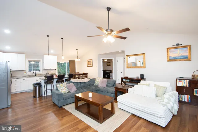 a living room with furniture kitchen view and a chandelier