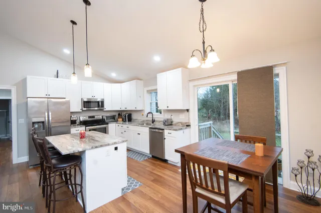 a kitchen with kitchen island a dining table chairs and white cabinets