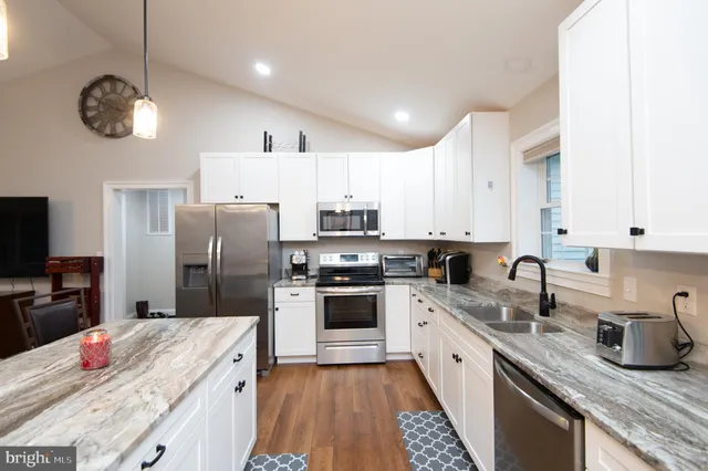 a kitchen with stainless steel appliances granite countertop a sink refrigerator and microwave