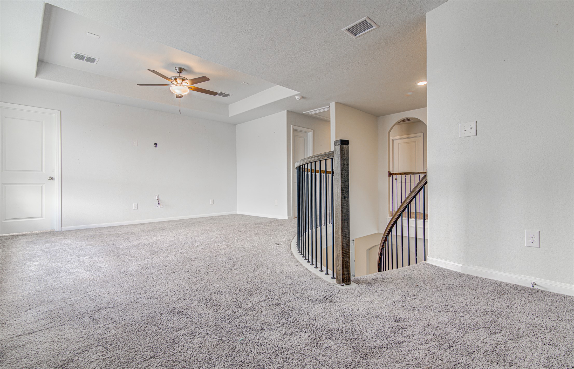 774 Cherrystone Loop Buda, TX 78610 - Photo 22 of 38 A spacious upper-level living area with soft gray carpeting and a gracefully curved staircase.