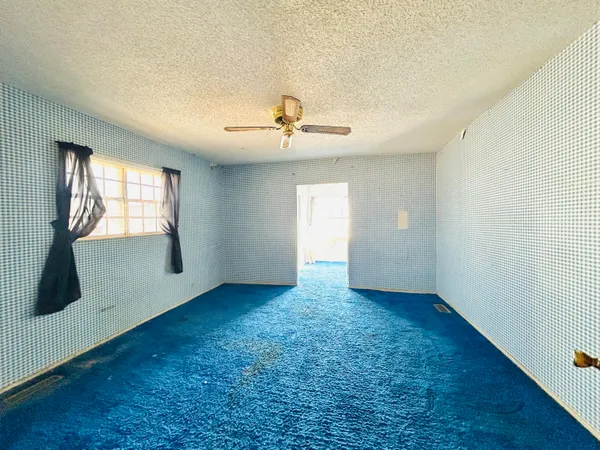 an empty room with windows and ceiling fan