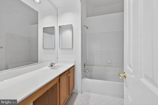 a bathroom with a tub sink shower and two mirror