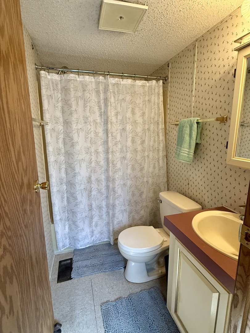 23 Walnut Street Minooka, IL 60447 - Photo 15 of 17 a bathroom with a sink a toilet a mirror and shower curtain