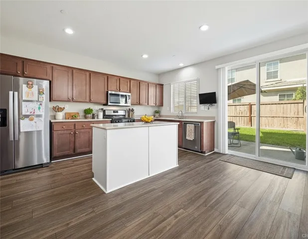 a kitchen with stainless steel appliances granite countertop a refrigerator a stove top oven a sink dishwasher and white cabinets with wooden floor