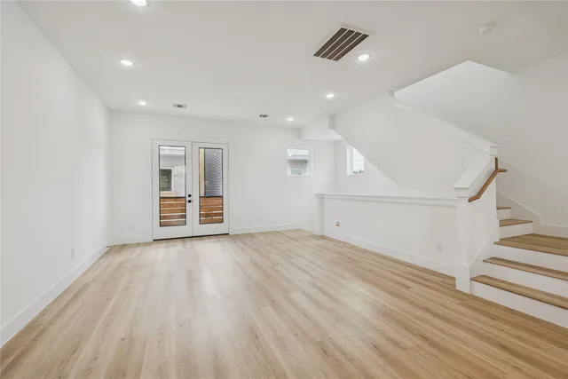 a view of an empty room with wooden floor and a ceiling fan