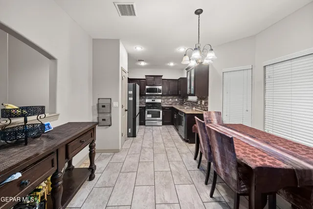 a kitchen with kitchen island a dining table chairs stainless steel appliances and cabinets