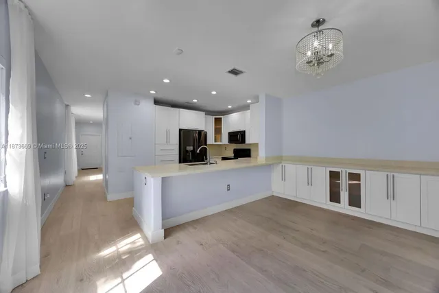 a large white kitchen with kitchen island a sink stainless steel appliances and cabinets