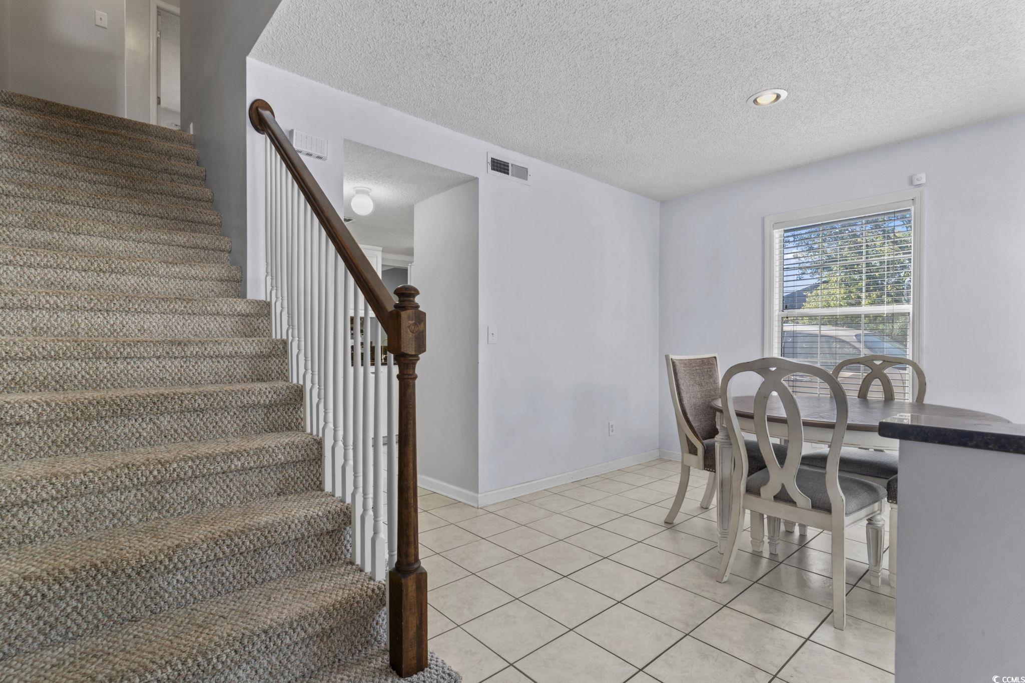 712 67th Avenue North, Unit 2A Myrtle Beach, SC 29572 - Photo 13 of 30 Dining space with a textured ceiling, light tile patterned flooring, and stairs