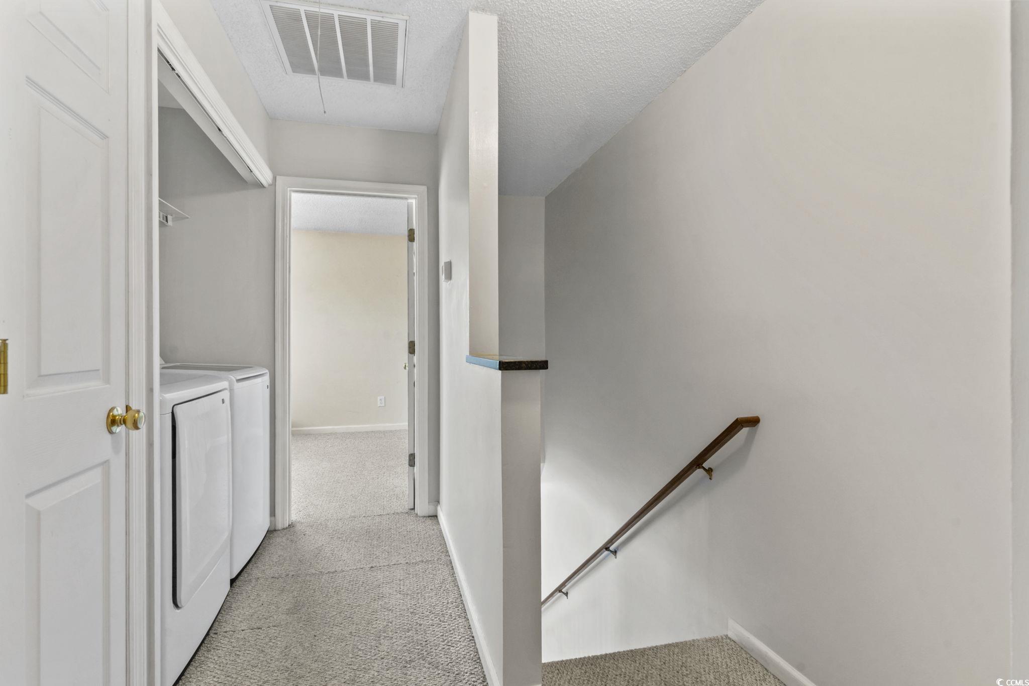 712 67th Avenue North, Unit 2A Myrtle Beach, SC 29572 - Photo 14 of 30 Hallway with light carpet, an upstairs landing, attic access, a textured ceiling, and washer and clothes dryer