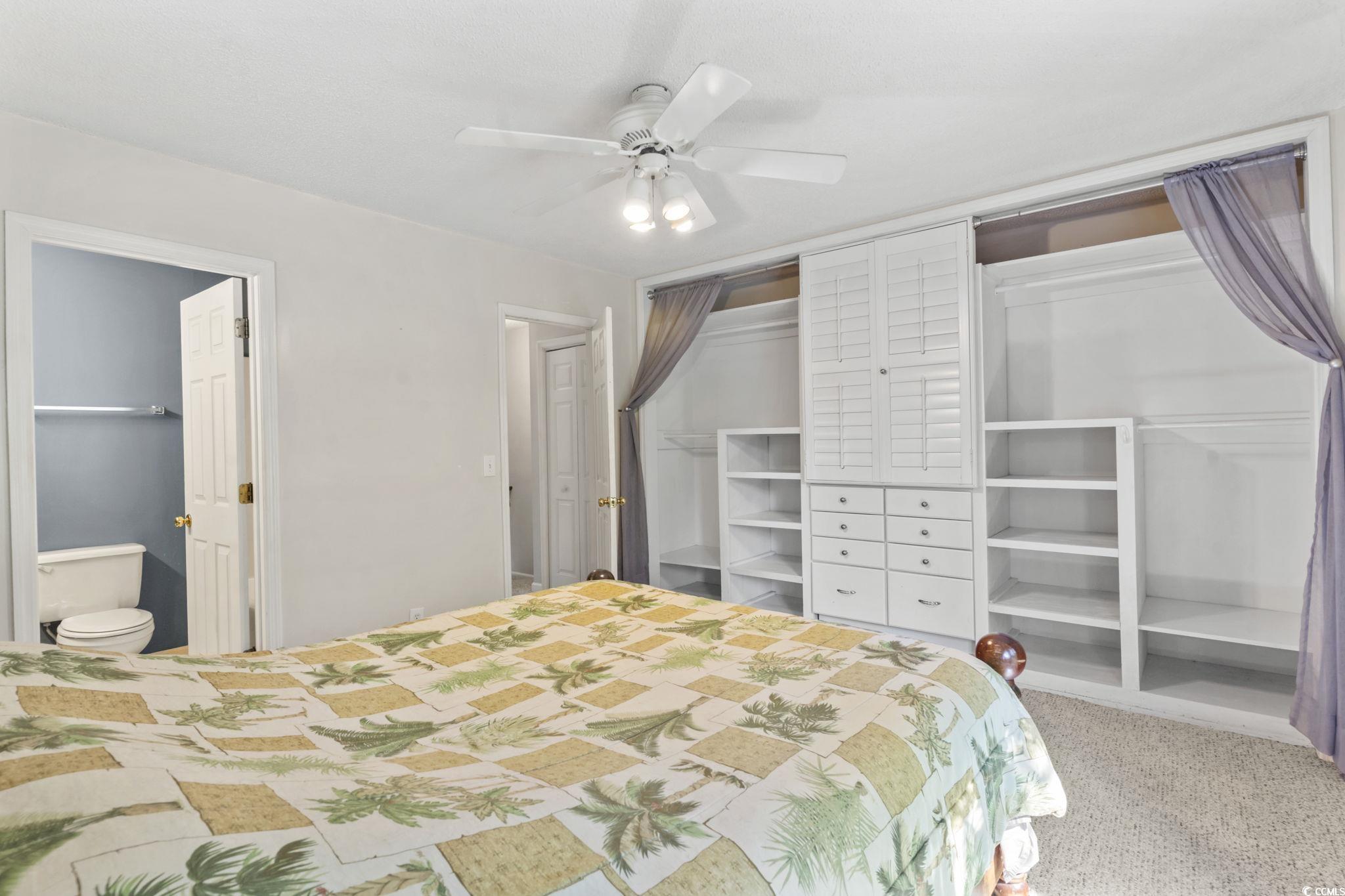 712 67th Avenue North, Unit 2A Myrtle Beach, SC 29572 - Photo 15 of 30 Bedroom with a closet, light carpet, a ceiling fan, and ensuite bath