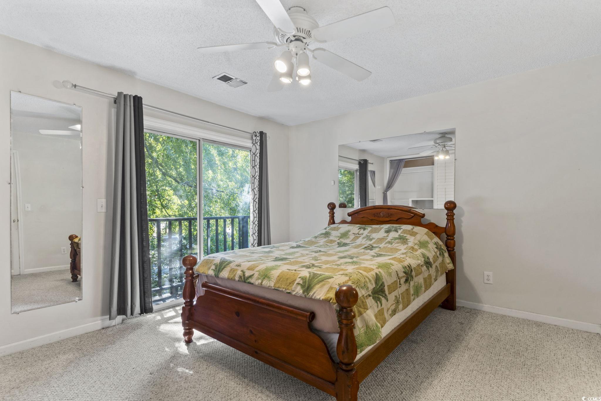 712 67th Avenue North, Unit 2A Myrtle Beach, SC 29572 - Photo 17 of 30 Bedroom featuring access to exterior, carpet, a textured ceiling, and a ceiling fan