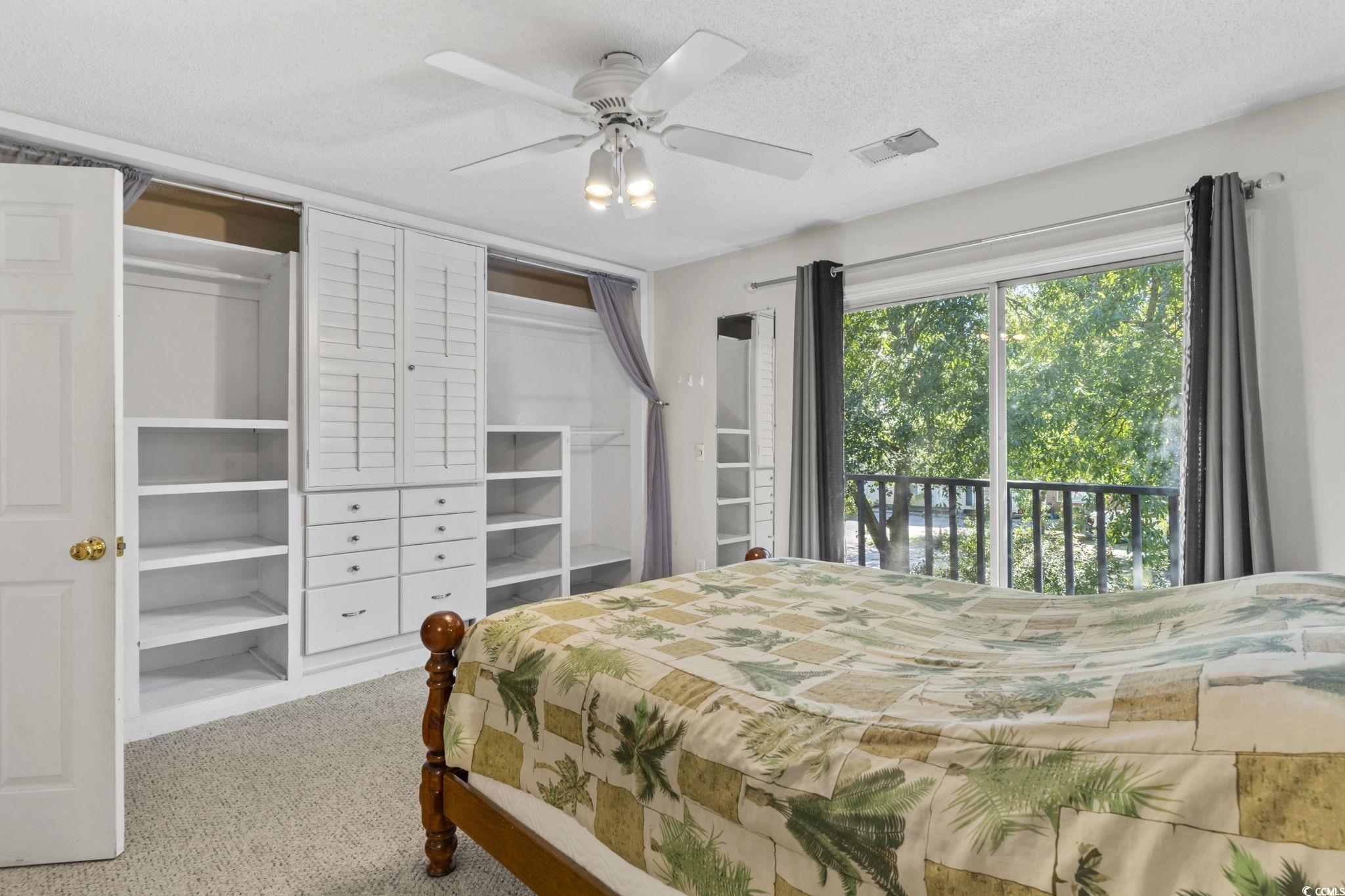 712 67th Avenue North, Unit 2A Myrtle Beach, SC 29572 - Photo 18 of 30 Bedroom with a textured ceiling, carpet, ceiling fan, multiple closets, and access to exterior