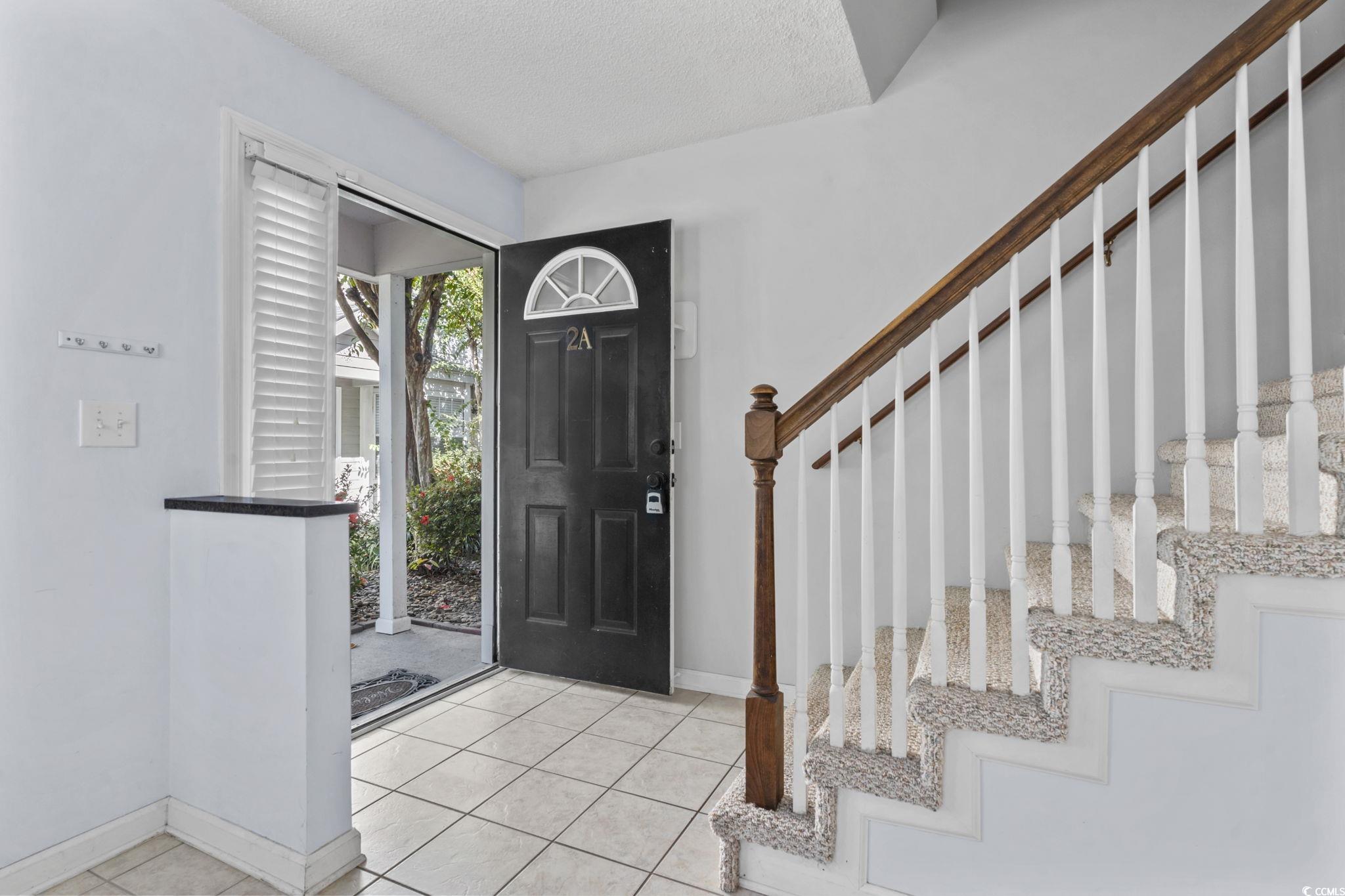 712 67th Avenue North, Unit 2A Myrtle Beach, SC 29572 - Photo 3 of 30 Foyer entrance with light tile patterned floors, a textured ceiling, and stairs