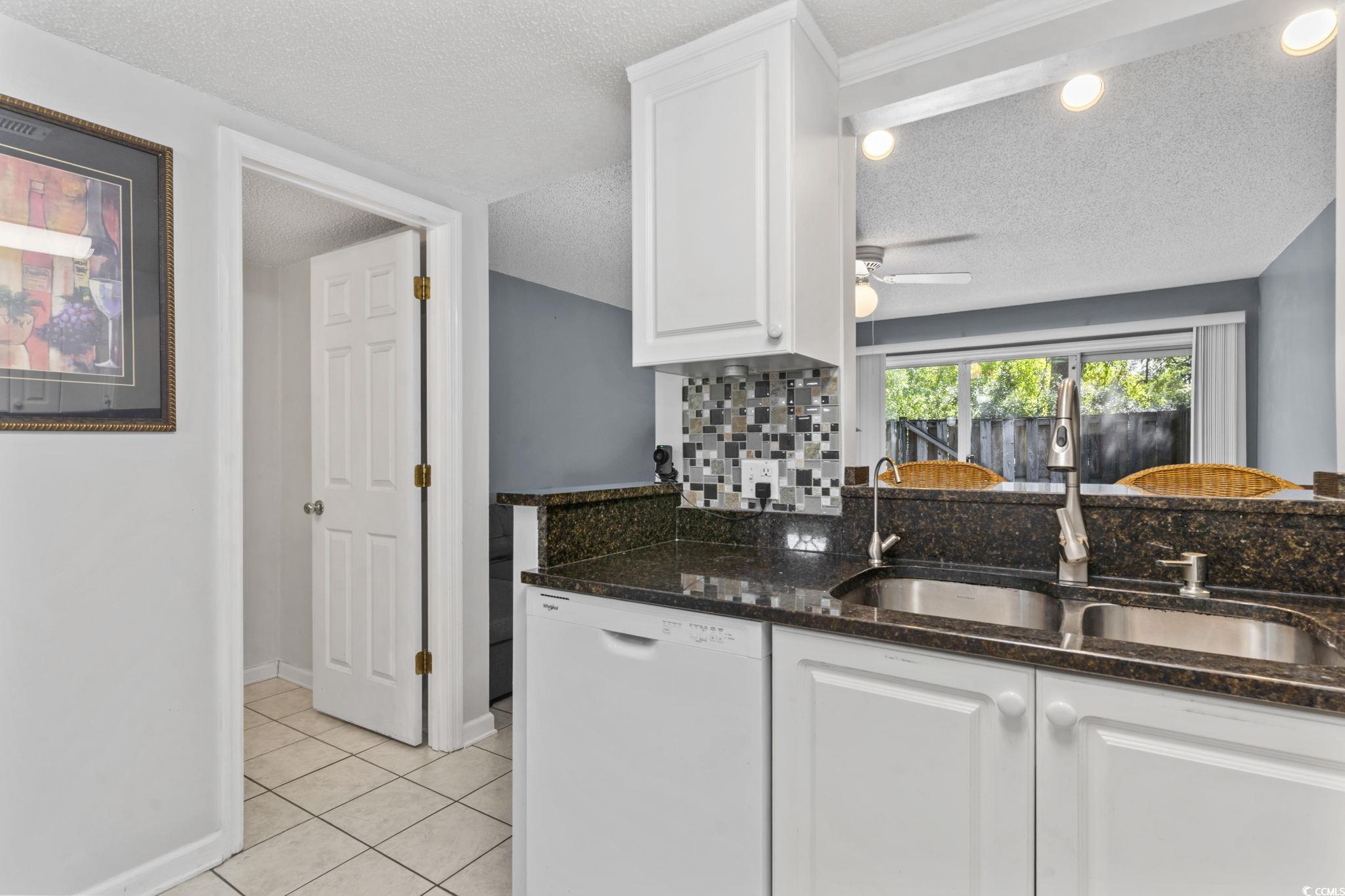712 67th Avenue North, Unit 2A Myrtle Beach, SC 29572 - Photo 6 of 30 Kitchen with white cabinetry, dishwasher, light tile patterned flooring, dark stone countertops, and a textured ceiling