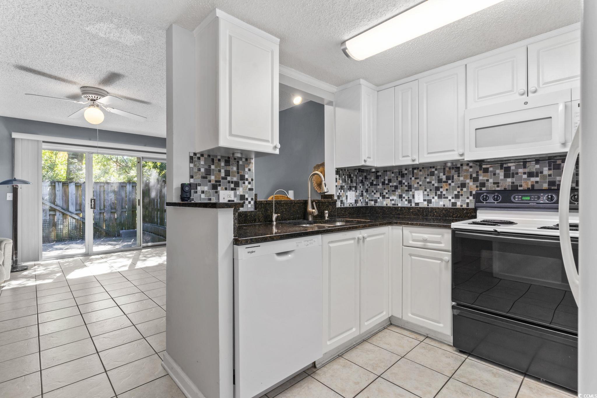 712 67th Avenue North, Unit 2A Myrtle Beach, SC 29572 - Photo 8 of 30 Kitchen featuring white appliances, backsplash, light tile patterned floors, white cabinetry, and a ceiling fan