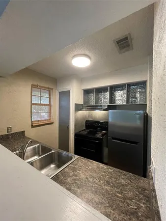 a kitchen with granite countertop a refrigerator and a sink