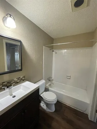 a bathroom with a bathtub shower sink vanity mirror and toilet