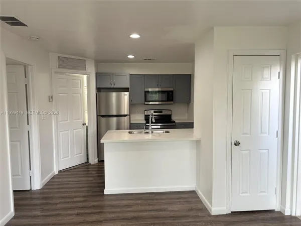 a view of kitchen with stainless steel appliances wooden floor and window