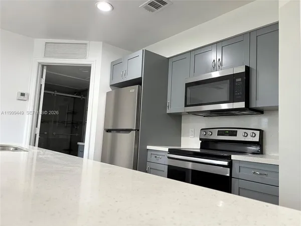 a kitchen with stainless steel appliances kitchen island granite countertop a refrigerator and a stove top oven