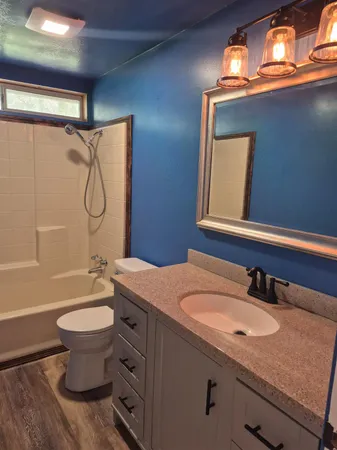 a bathroom with a granite countertop sink toilet and shower
