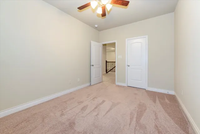 a view of an empty room and chandelier fan