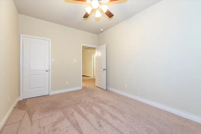 an empty room with a chandelier fan and windows