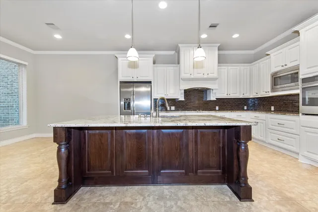 a large kitchen with granite countertop a stove a sink a refrigerator and a fireplace