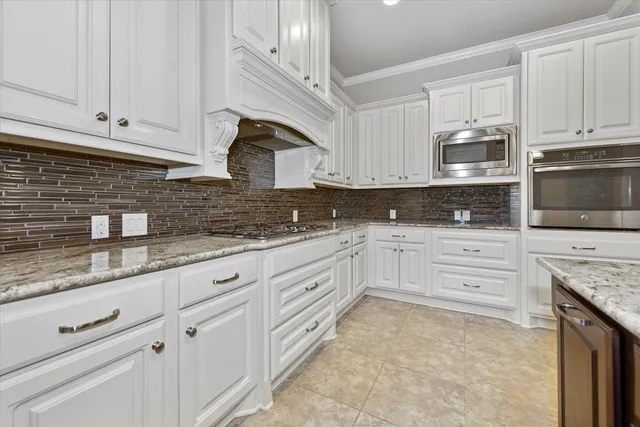 a kitchen with granite countertop white cabinets stainless steel appliances and a sink