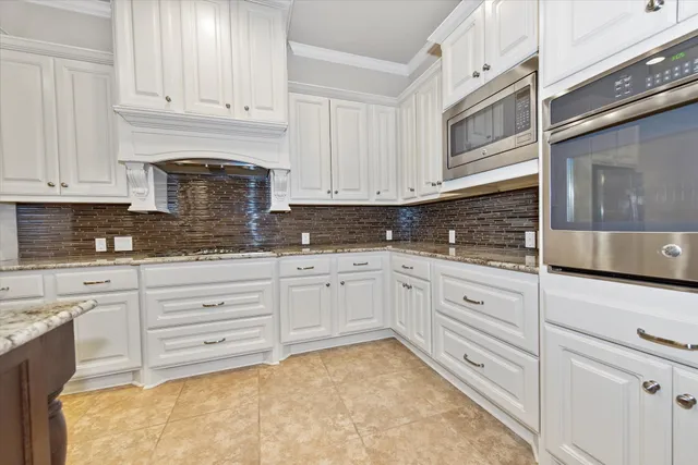 a kitchen with granite countertop white cabinets and stainless steel appliances
