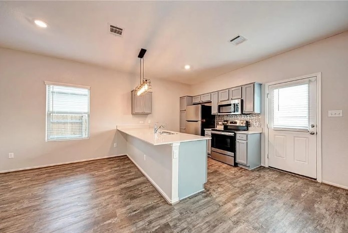 817 Circle Way, Unit 7I Jarrell, TX 76537 - Photo 12 of 33 Kitchen with appliances with stainless steel finishes, gray cabinets, a breakfast bar, hanging light fixtures, and light wood-style floors