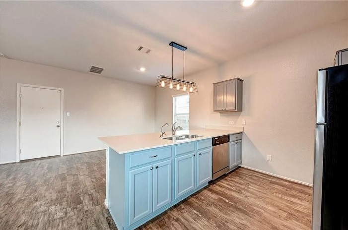 817 Circle Way, Unit 7I Jarrell, TX 76537 - Photo 13 of 33 Kitchen with stainless steel appliances, dark wood finished floors, pendant lighting, a peninsula, and blue cabinets