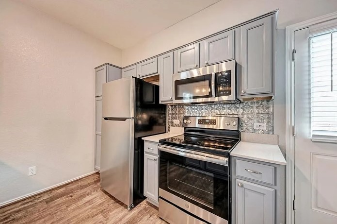 817 Circle Way, Unit 7I Jarrell, TX 76537 - Photo 14 of 33 Kitchen with gray cabinets, appliances with stainless steel finishes, tasteful backsplash, and light wood-style floors