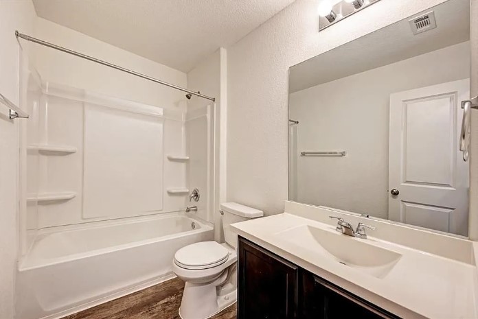 817 Circle Way, Unit 7I Jarrell, TX 76537 - Photo 30 of 33 Bathroom with vanity, shower / washtub combination, dark wood-type flooring, and a textured ceiling