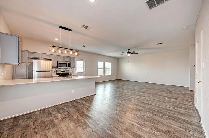 817 Circle Way, Unit 7I Jarrell, TX 76537 - Photo 8 of 33 Kitchen featuring gray cabinets, appliances with stainless steel finishes, pendant lighting, backsplash, and dark wood-type flooring