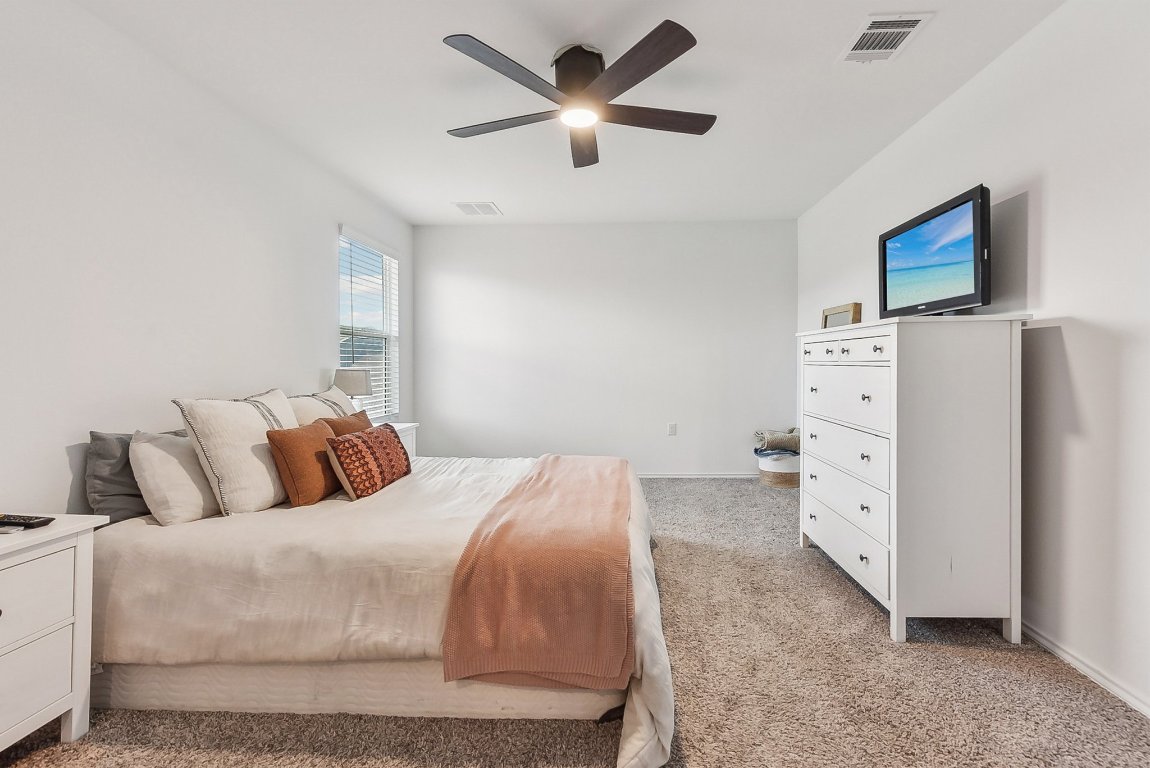 5908 Eden Drive Austin, TX 78747 - Photo 18 of 31 a bedroom with a white bed and a chandelier