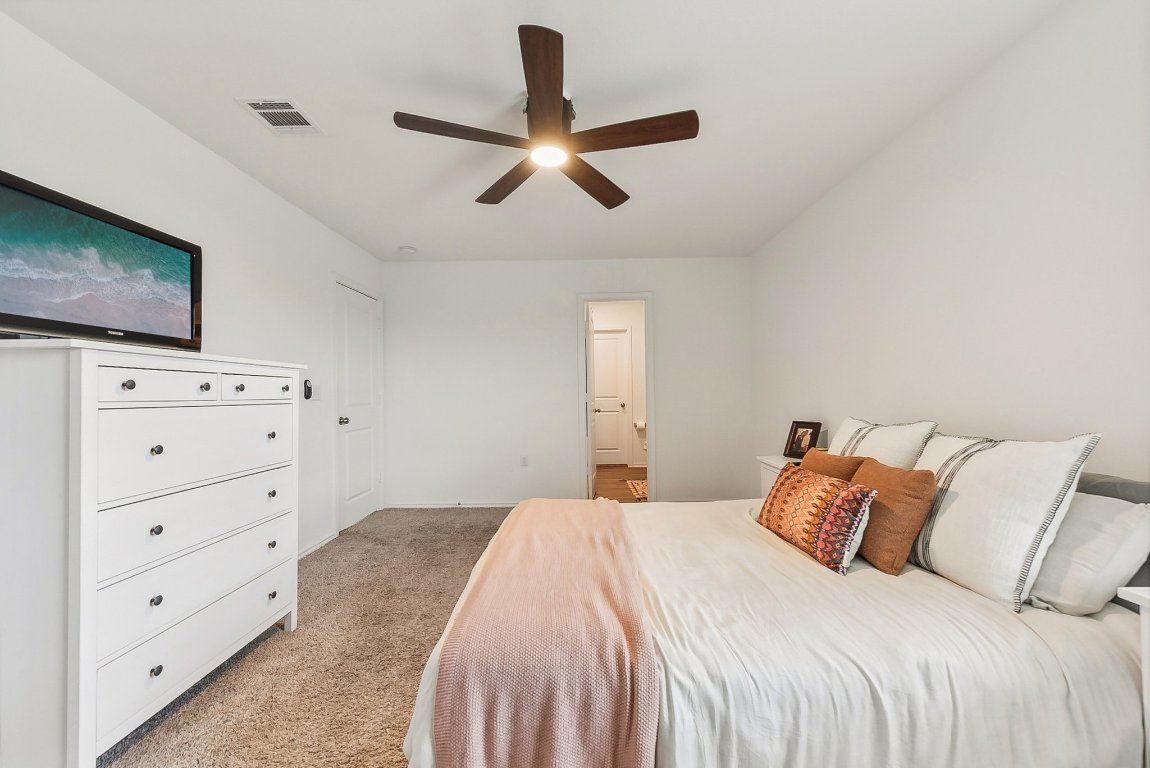 5908 Eden Drive Austin, TX 78747 - Photo 19 of 31 a bedroom with a bed and a flat tv screen on dresser