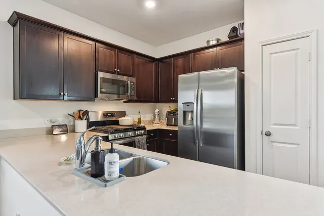 a kitchen with stainless steel appliances granite countertop a refrigerator a stove and a sink with wooden floors