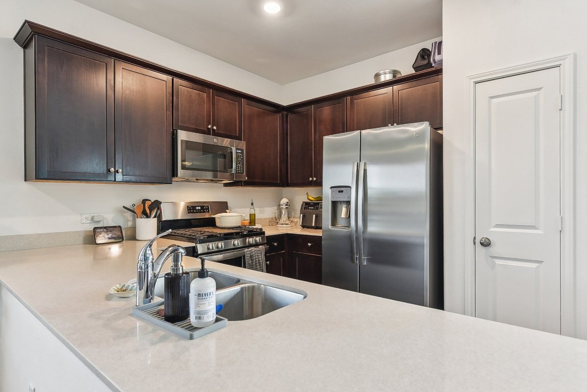 5908 Eden Drive Austin, TX 78747 - Photo 7 of 31 a kitchen with stainless steel appliances granite countertop a refrigerator a stove and a sink with wooden floors