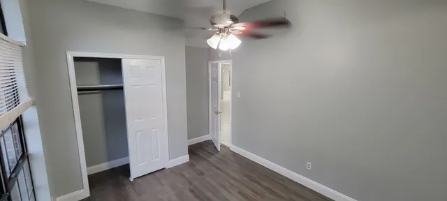 en empty room with wooden floor fan and windows