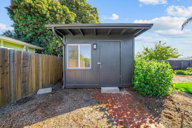 a view of a wooden house with a yard and potted plants