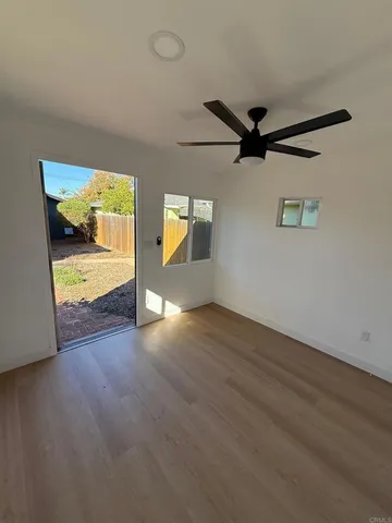 an empty room with wooden floor and a ceiling fan
