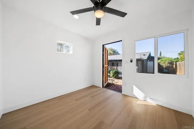 a view of an empty room with window and wooden floor